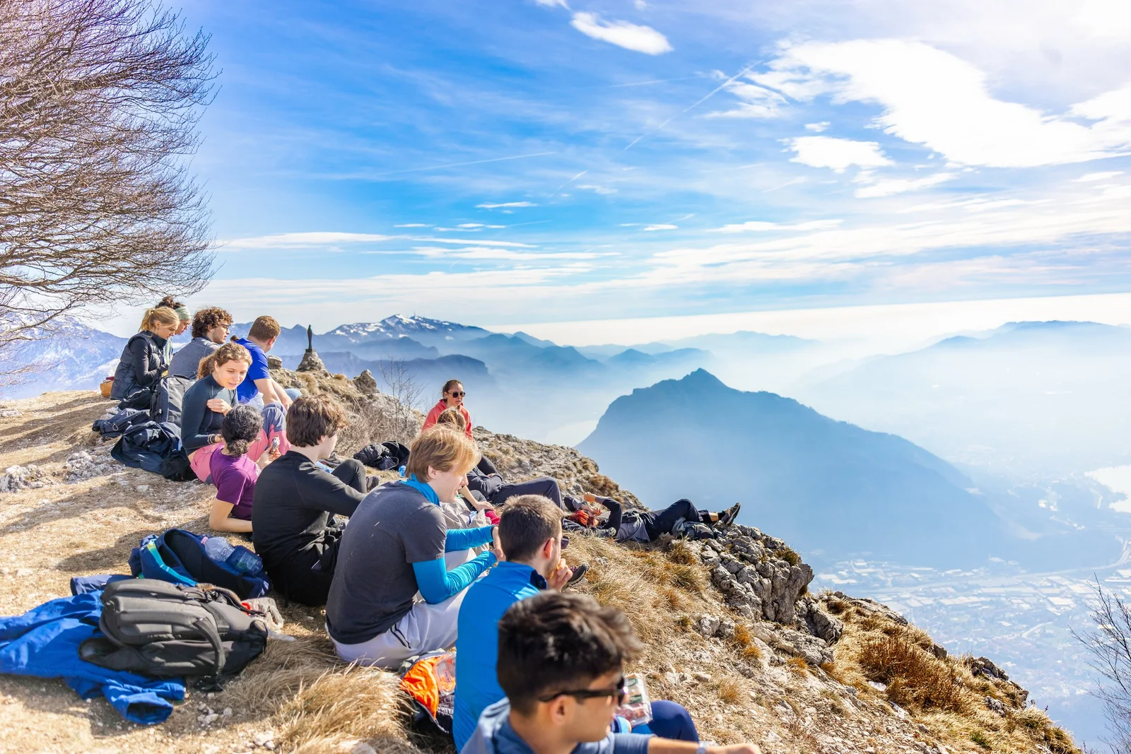 A group of hikers resting at a mountain viewpoint overlooking a lake